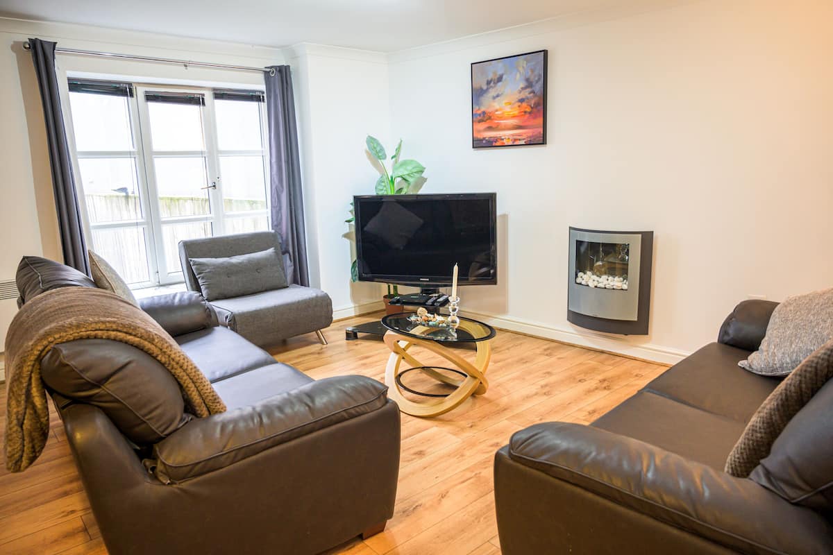 A living room with a sofa, a coffee table, a TV, and a plant.