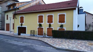 A building with a yellow facade, multiple wooden shutters, and a tiled entrance.