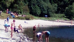 A rocky beach with people swimming and relaxing.