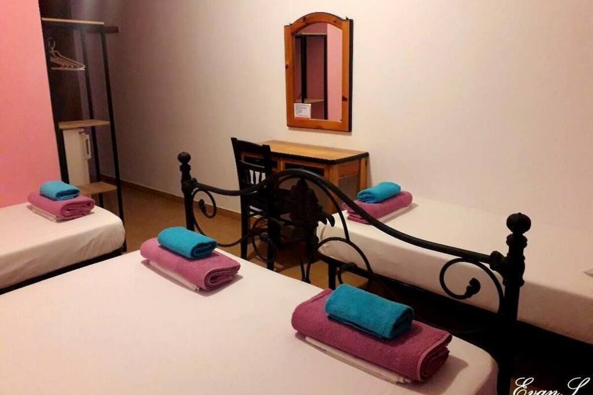 A hotel room with two beds, a desk, and a mirror.