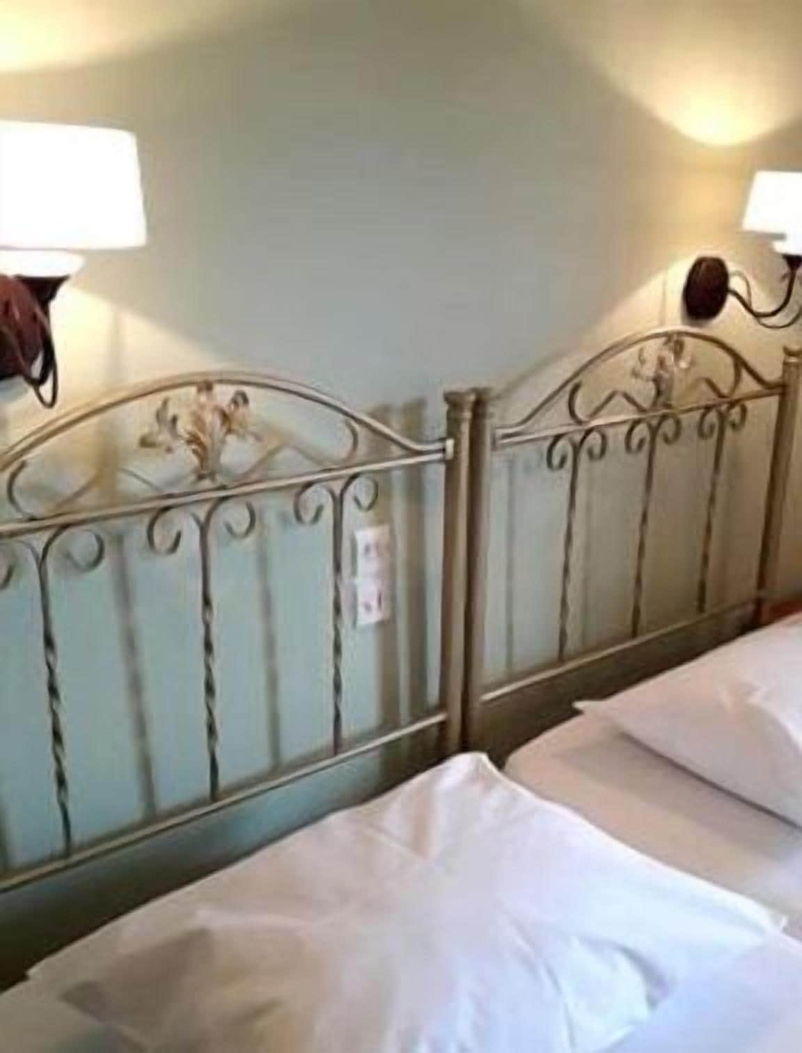 A bed with a metal headboard and two wall-mounted lamps.