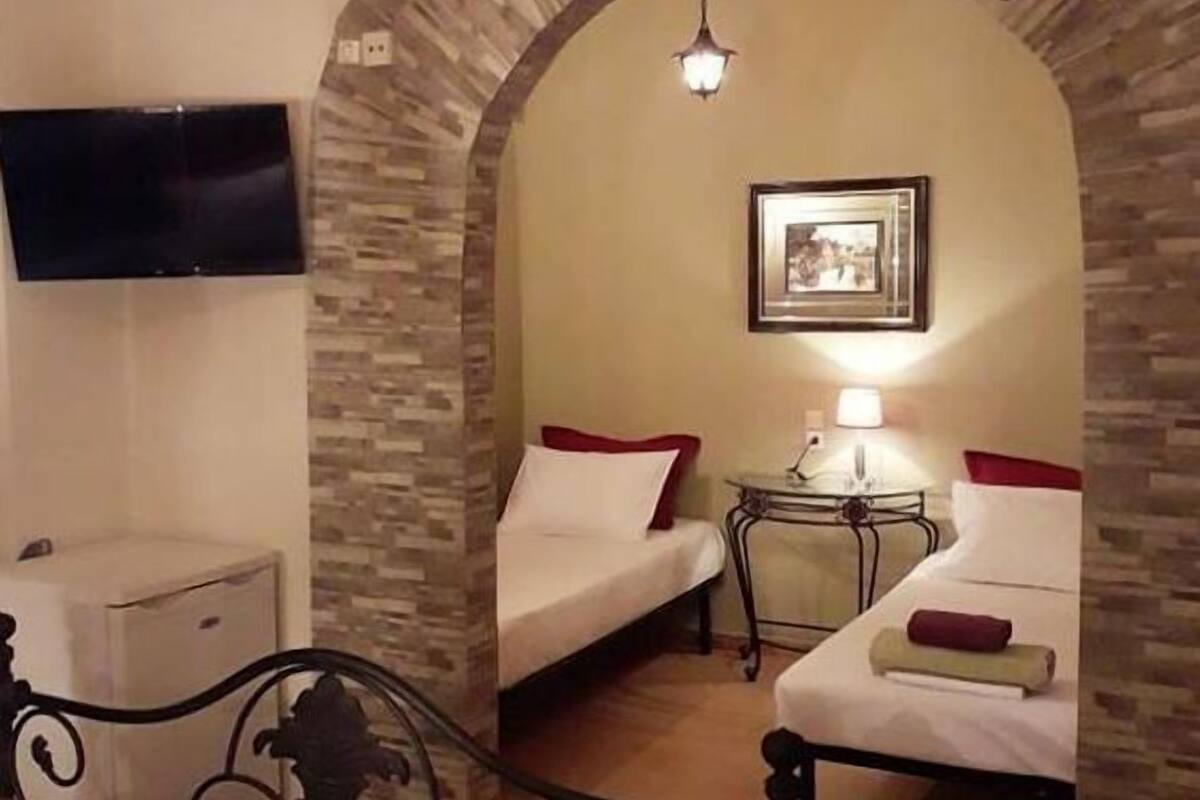 A room with two beds, a TV, a lamp, and a picture on the wall.