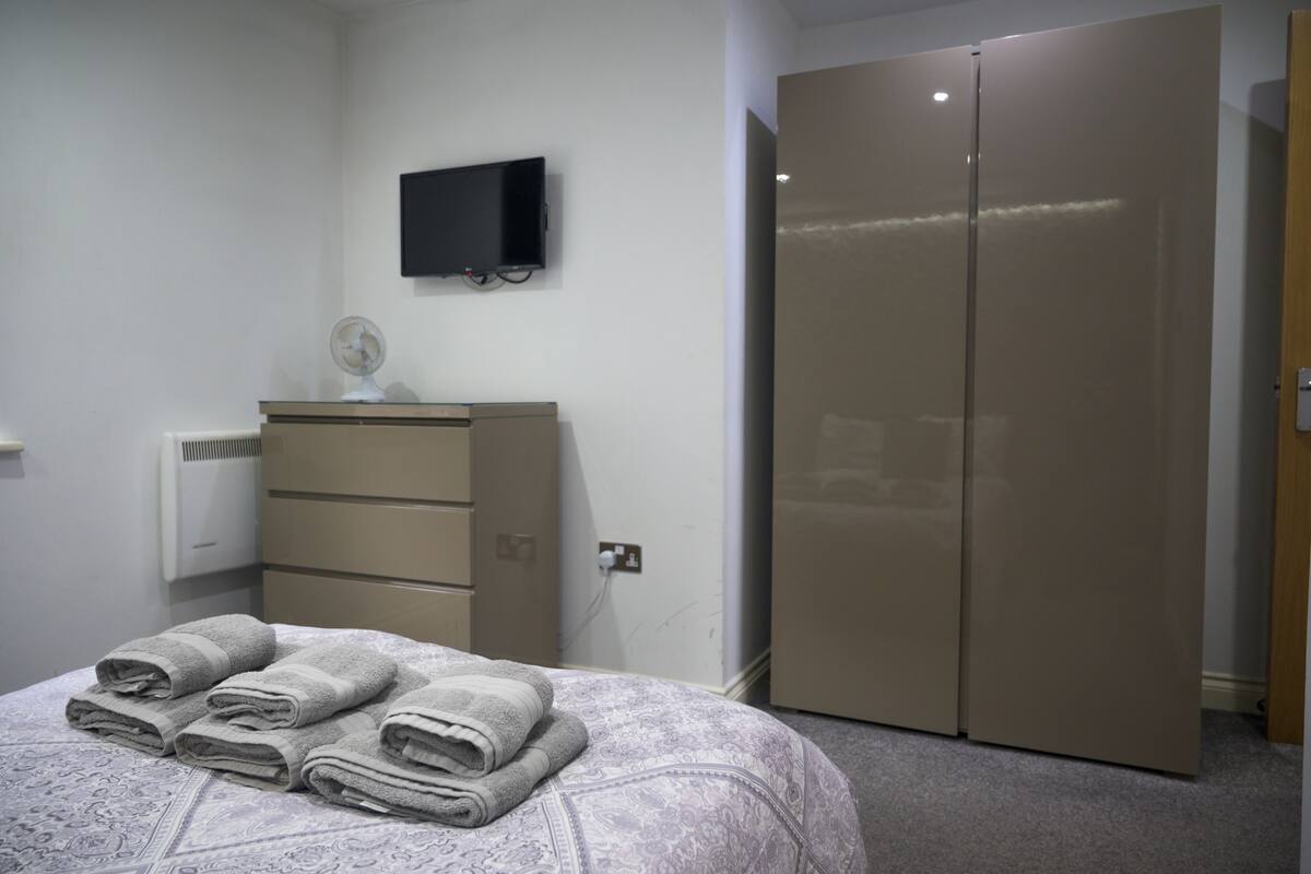A bedroom with a bed, a dresser, a television, and a wardrobe.