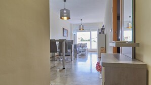 A spacious hallway with a marble floor leading to a dining area with a table and chairs. - Beachfront apartment, with pool and urban areas. Zarati (Isla Cristina)