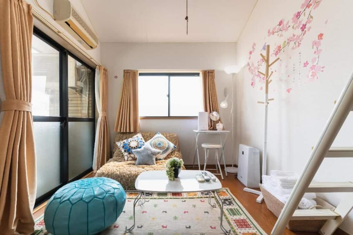 Ein gemütliches Wohnzimmer mit einer Couch, einem Couchtisch und einem fenster mit Vorhängen.