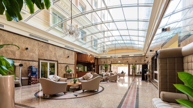 A spacious lobby with a high glass ceiling, comfortable seating areas, and a central chandelier. - Al Diyafa Furnished Suites (Doha)