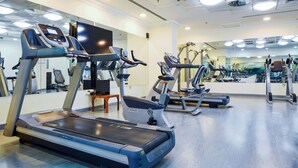 A gym with treadmills, elliptical machines, and a mirror wall. - Al Diyafa Furnished Suites (Doha)