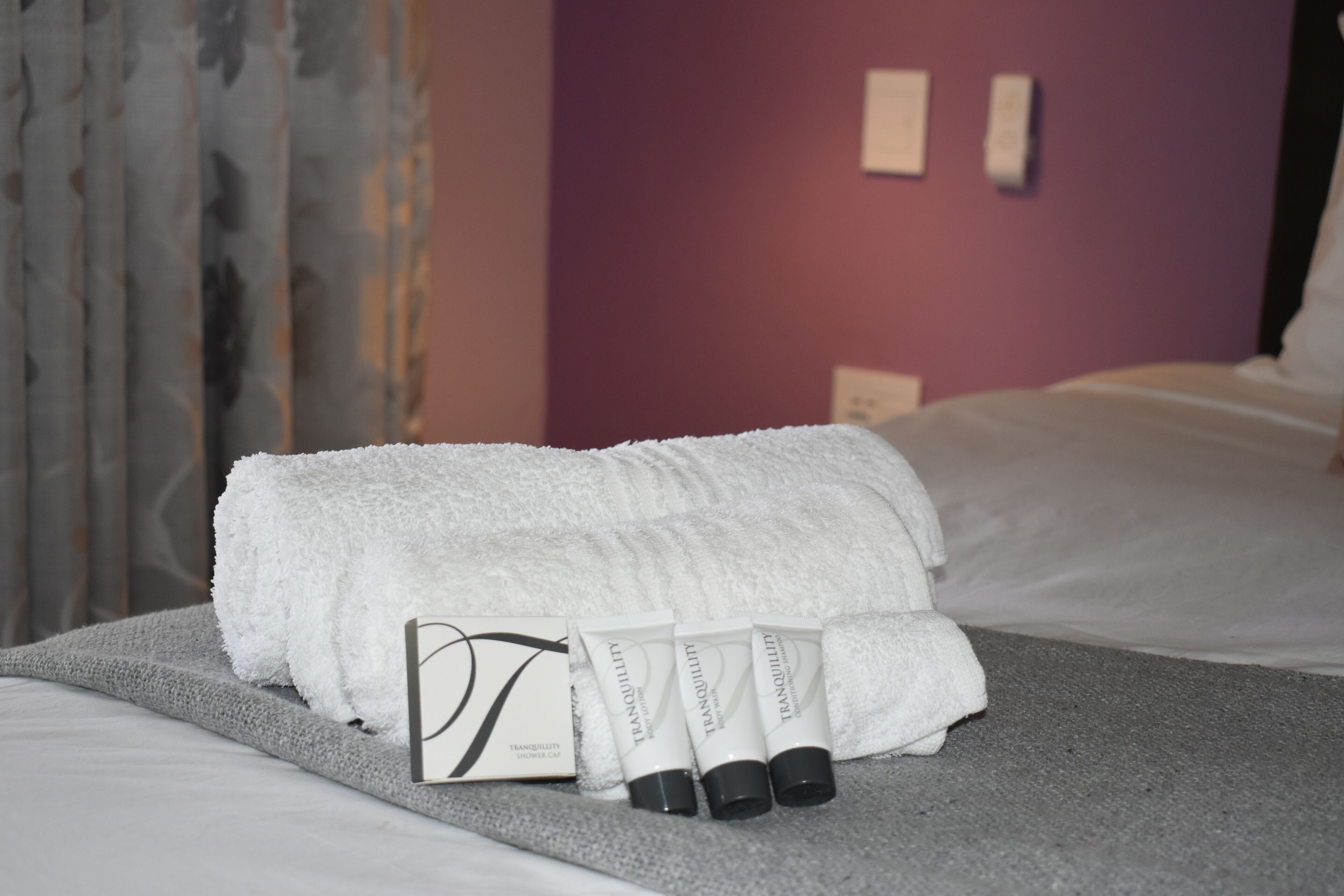 Una cama bien hecha con una toalla blanca y tres tubos de crema 'Tranquility'.