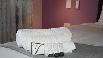 Una cama bien hecha con una toalla blanca y tres tubos de crema 'Tranquility'.
