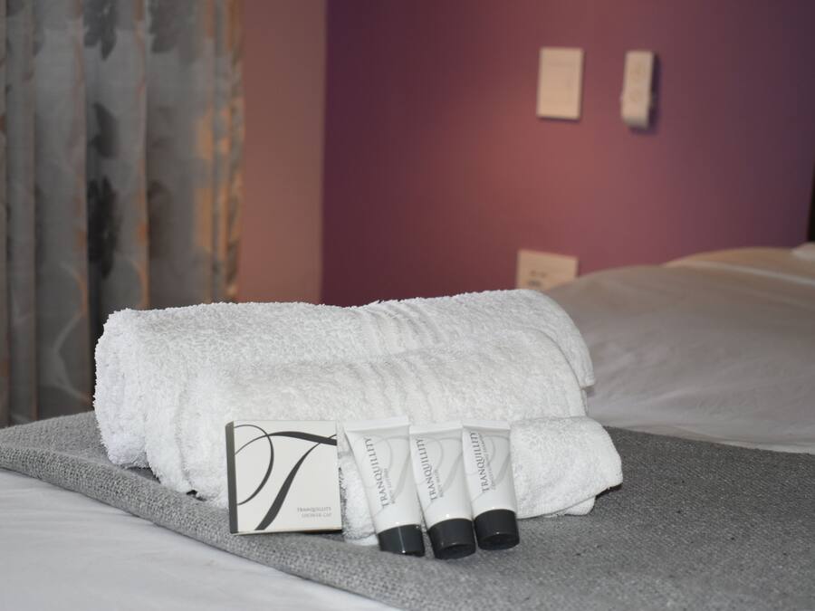 Una cama bien hecha con una toalla blanca y tres tubos de crema 'Tranquility'.