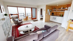 A modern living room with a sofa, coffee table, and a view to the outside.