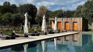 Una piscina al aire libre, sillones reclinables de piscina