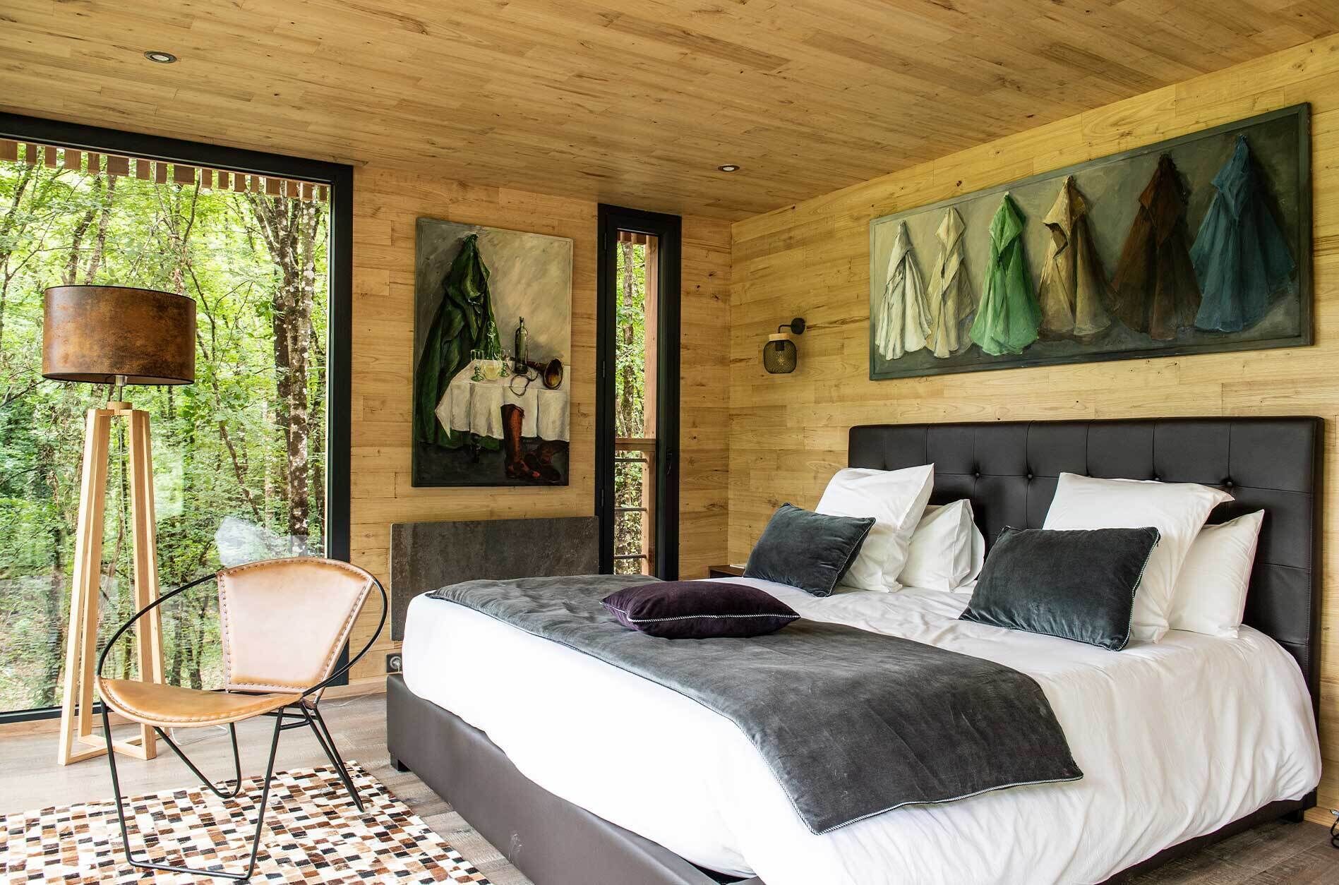 A bedroom with a large bed, a chair, and artwork on the walls.