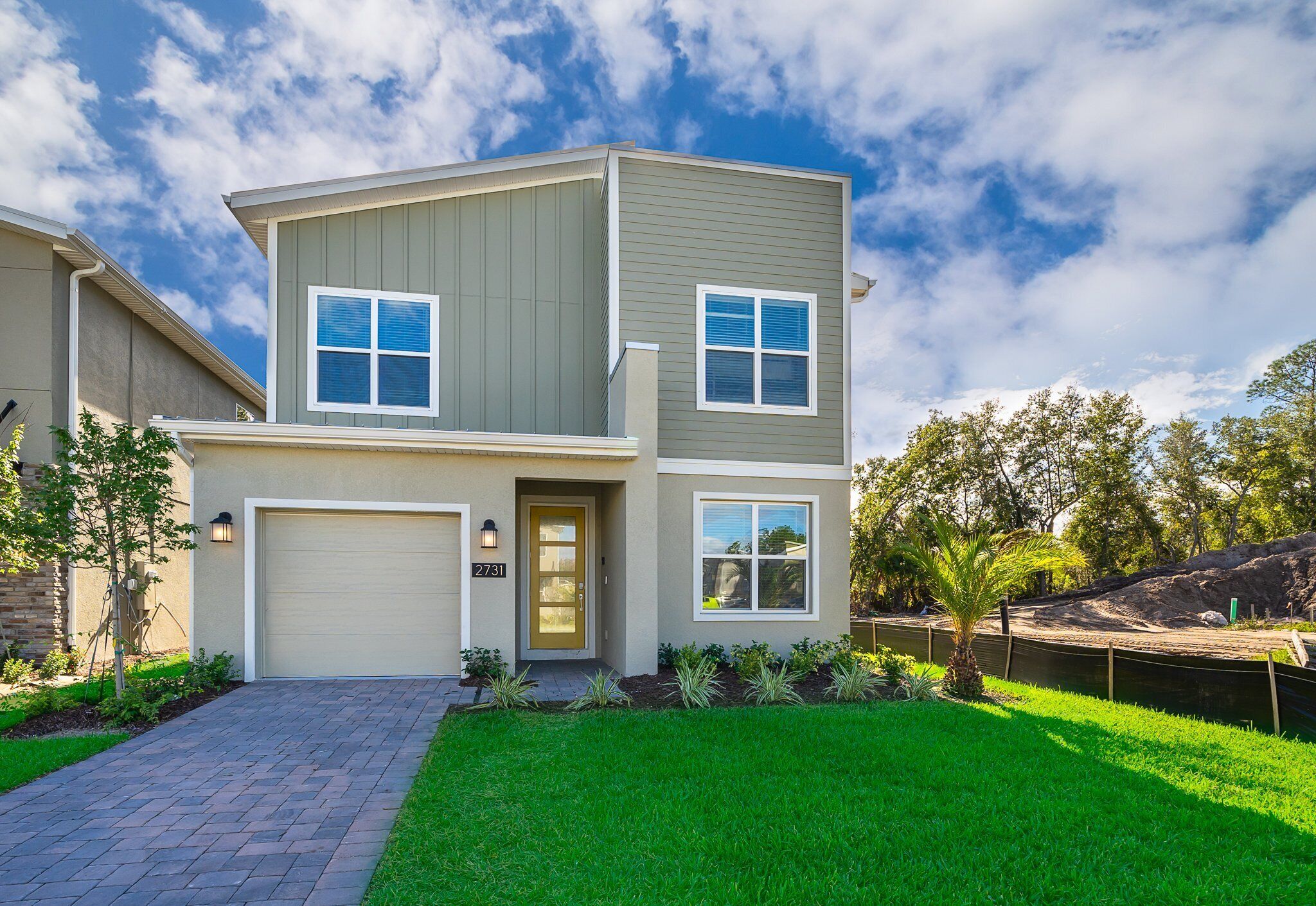A two-story house with a garage, a well-maintained lawn, and a small pond.
