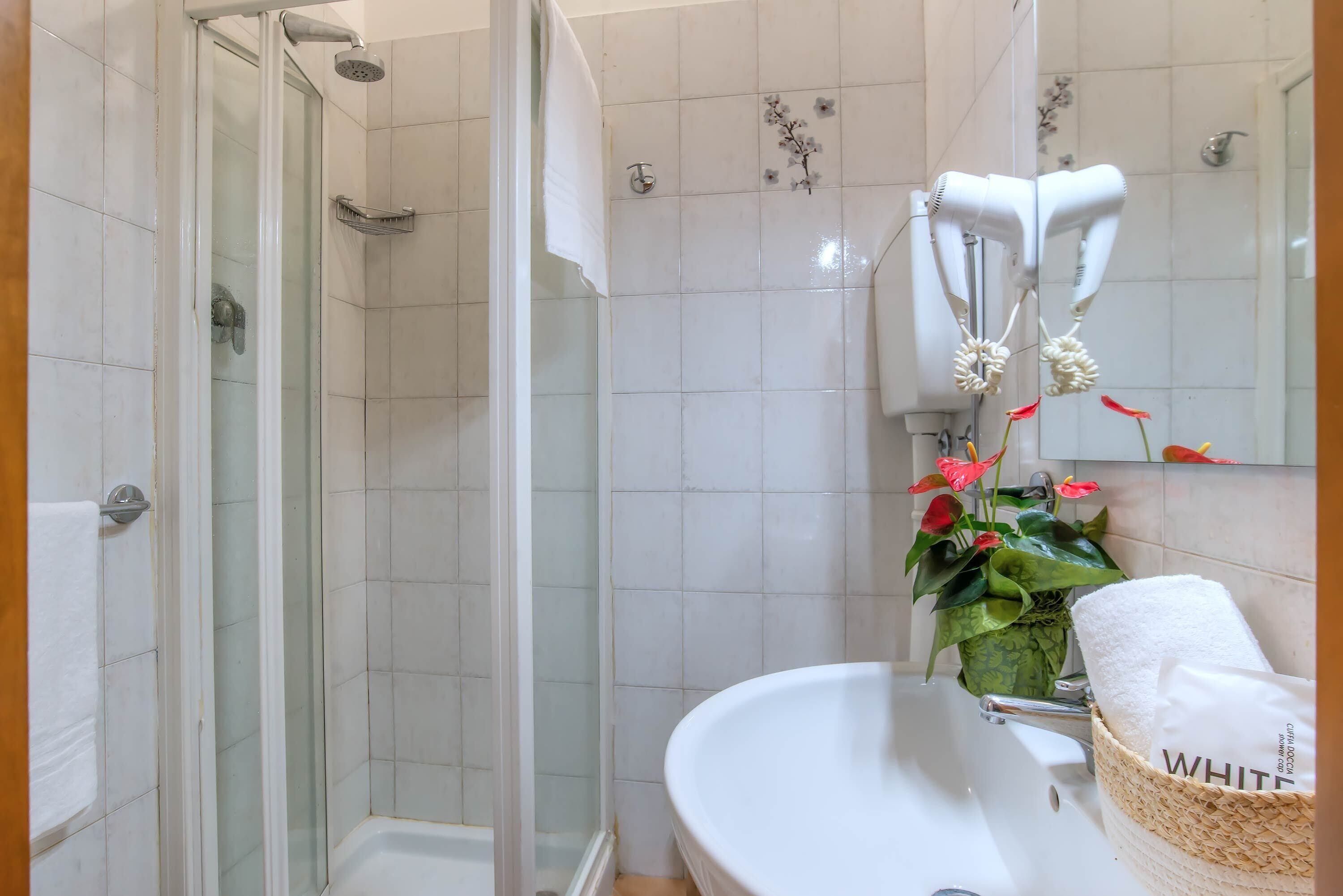 A bathroom with a glass-enclosed shower, a white sink, and a mirror with a towel rack.