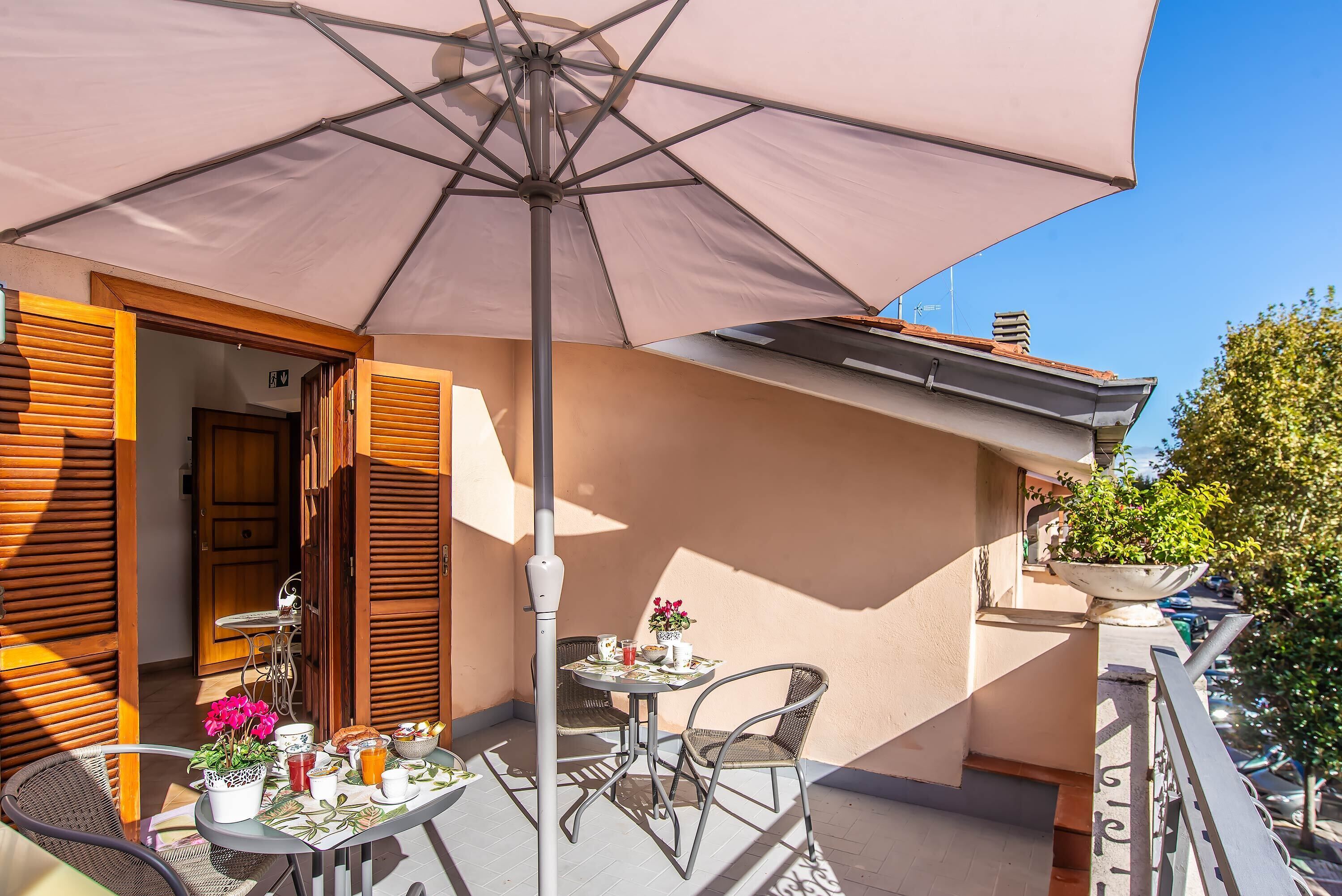 A balcony with a table, chairs, and a large umbrella.