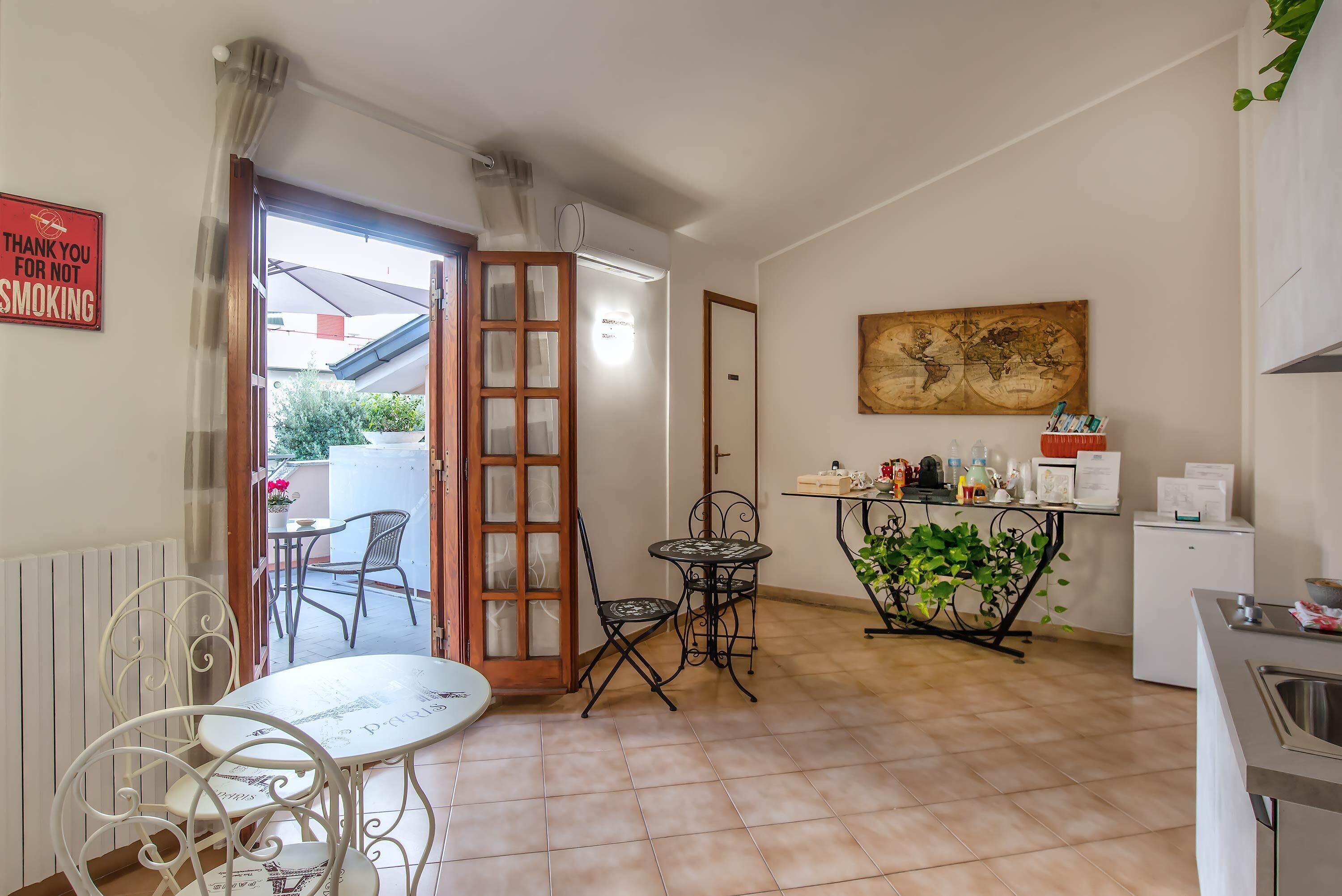 A compact kitchen with a dining area, a small refrigerator, and a potted plant.