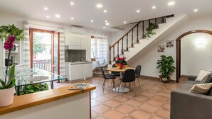 A modern kitchen with a dining area, a staircase, and a living room. - Plaza Rooms Ciampino (Ciampino)