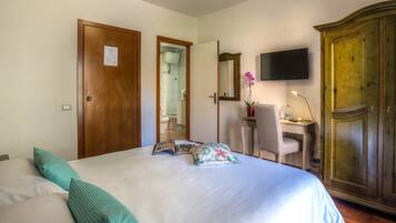 Una habitación de hotel con cama, escritorio, televisor y armario.