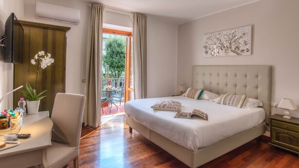 A bedroom with a large bed, a desk, a chair, and a TV. - Plaza Rooms Ciampino (Ciampino)