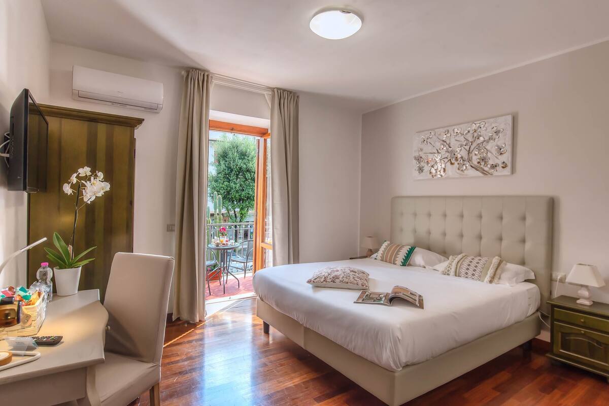 A bedroom with a large bed, a desk, a chair, and a TV.