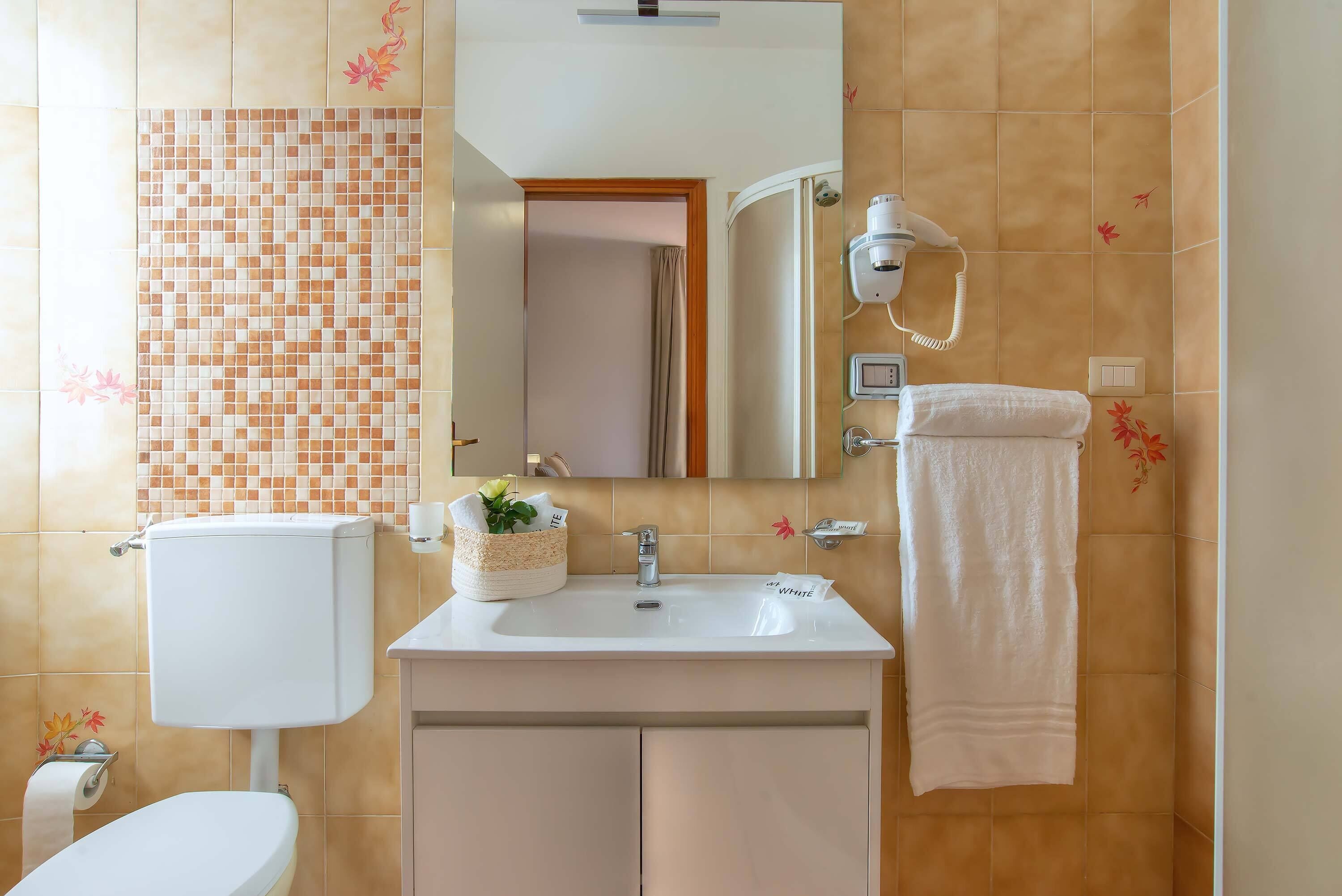 Un baño con inodoro, lavamanos y espejo.