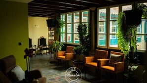 A cozy room with a large window, several chairs, and potted plants. - Hotel Fonte da Vila (Monção)