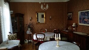 Une salle à manger avec une table ronde, deux chaises, un buffet et un miroir au mur.