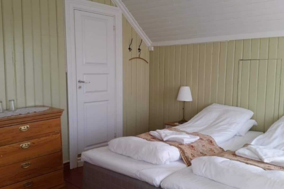 Quarto com cama, cómoda de madeira e porta.
