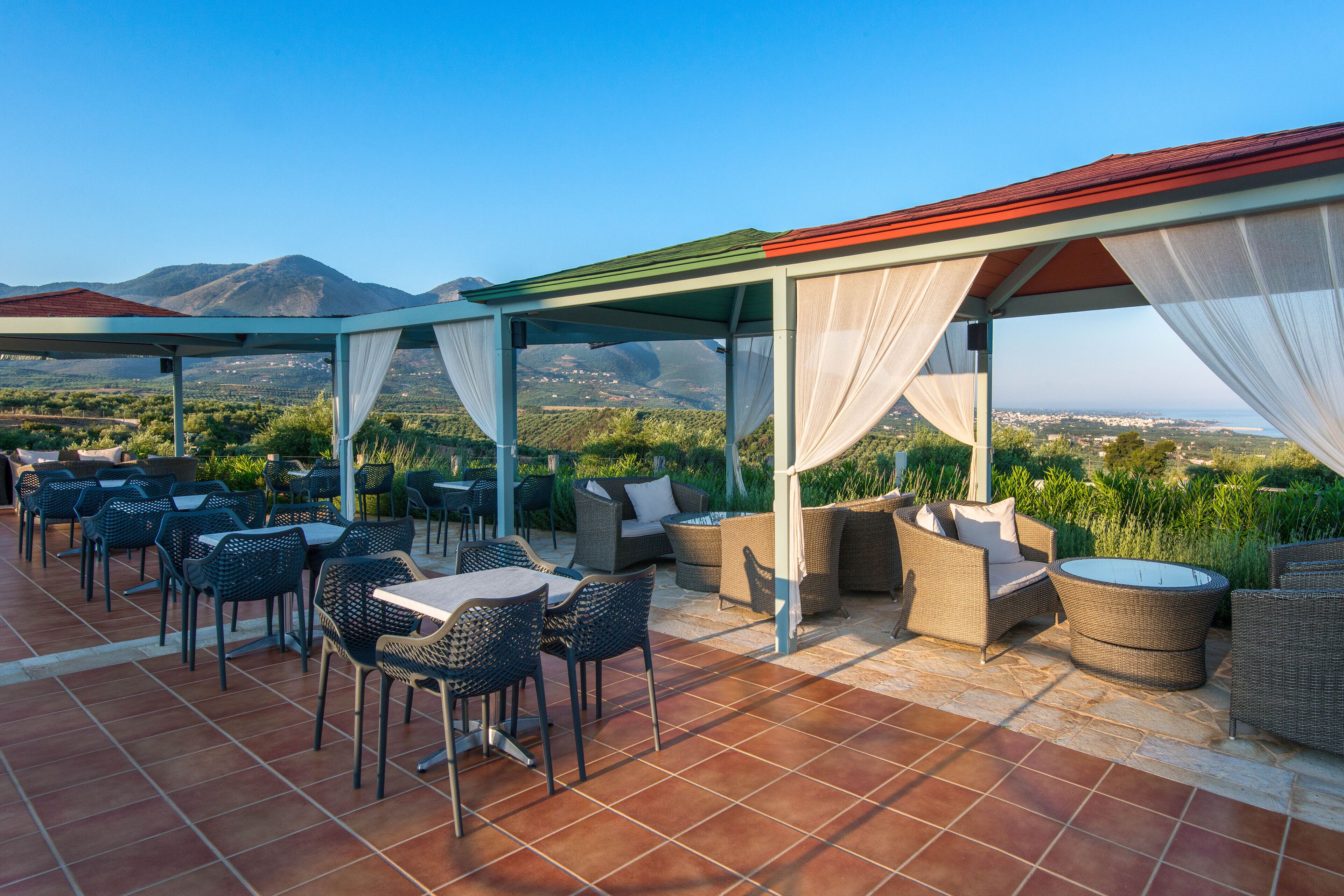Um terraço com mobiliário de exterior, área coberta e vista para montanhas ao longe.