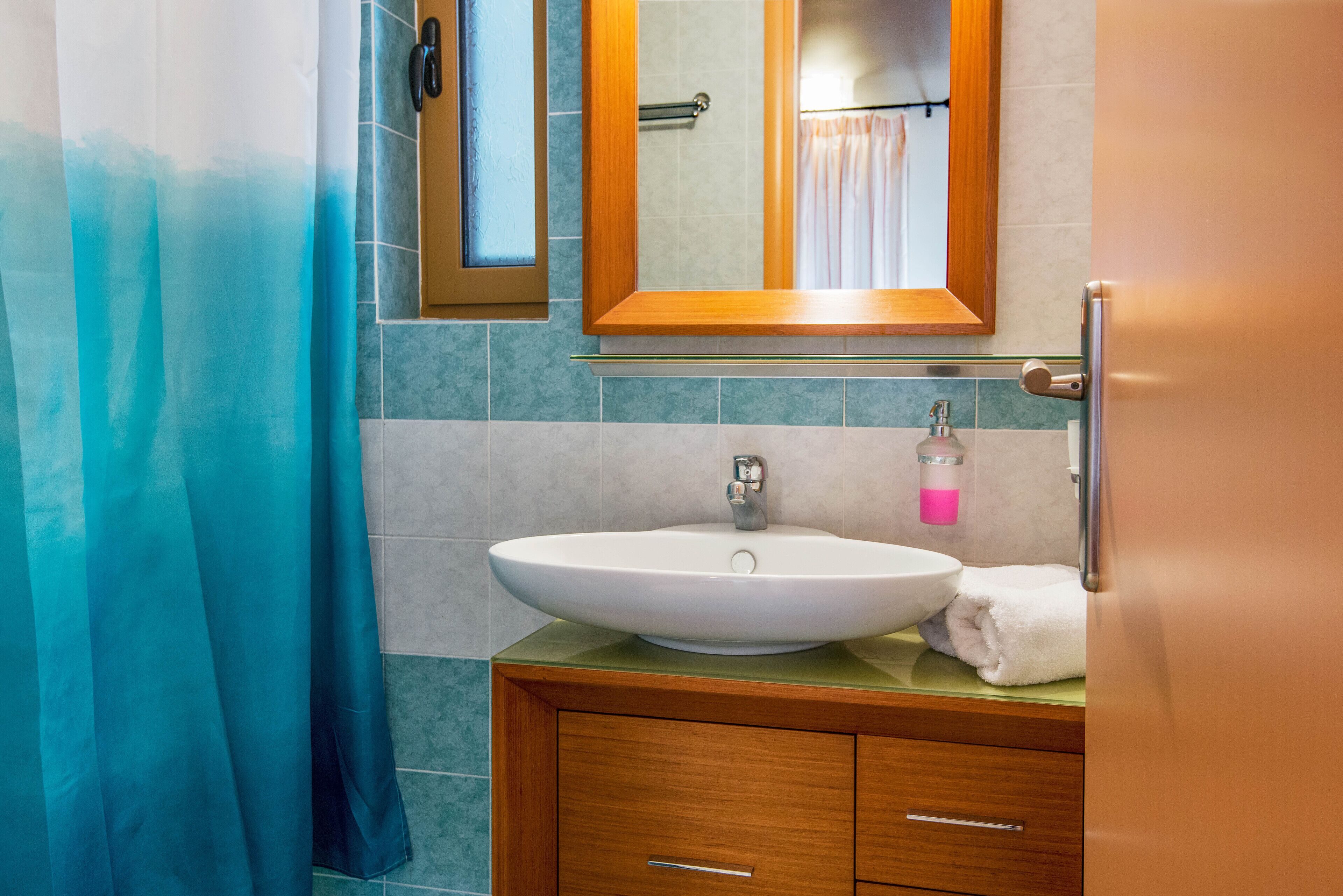 A bathroom with a large white sink, a mirror, and a shower curtain.