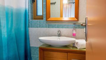 A bathroom with a large white sink, a mirror, and a shower curtain.
