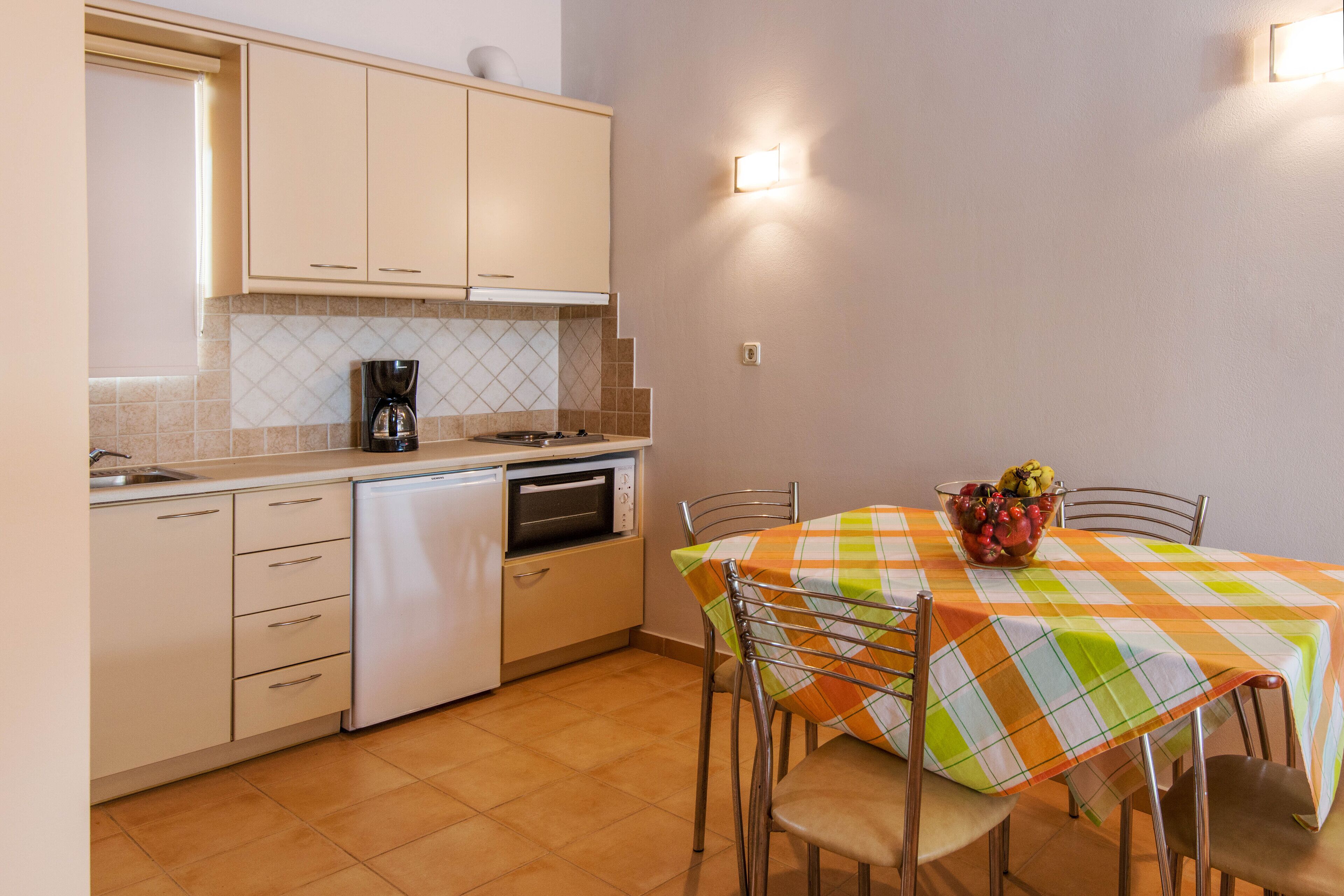 A compact kitchen with a dishwasher, oven, and a dining table with a checkered tablecloth.