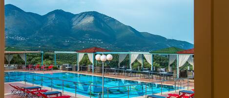 Un espace piscine avec des chaises longues rouges et une vue sur les montagnes.