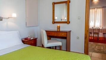 Habitación de hotel con cama, escritorio, silla, espejo y una vela encendida.