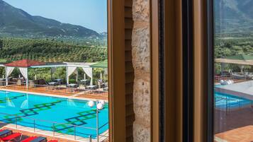 A poolside view with a mountain backdrop, outdoor seating, and a clear sky.