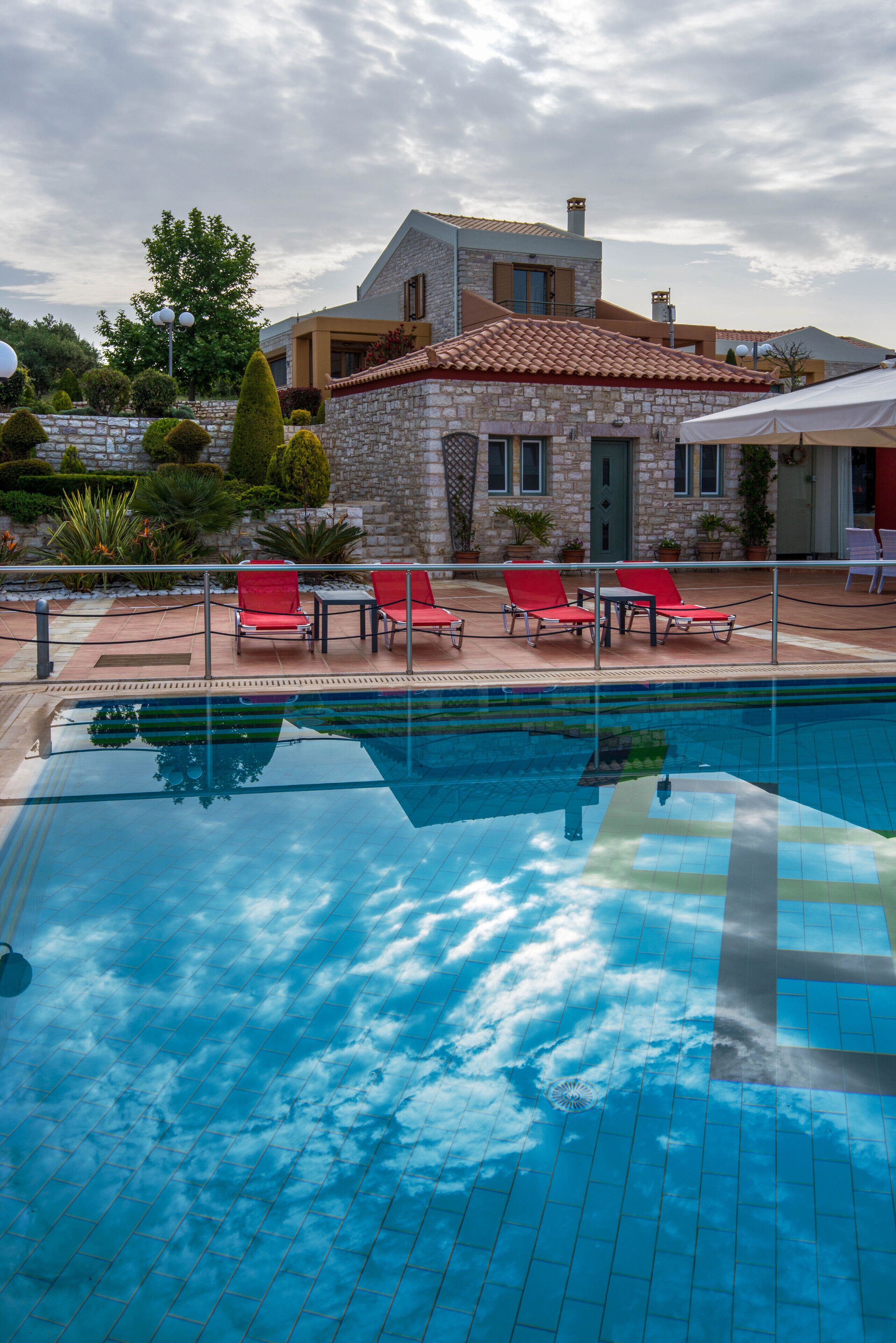 Une piscine avec des chaises longues rouges et un bâtiment en pierre en arrière-plan.