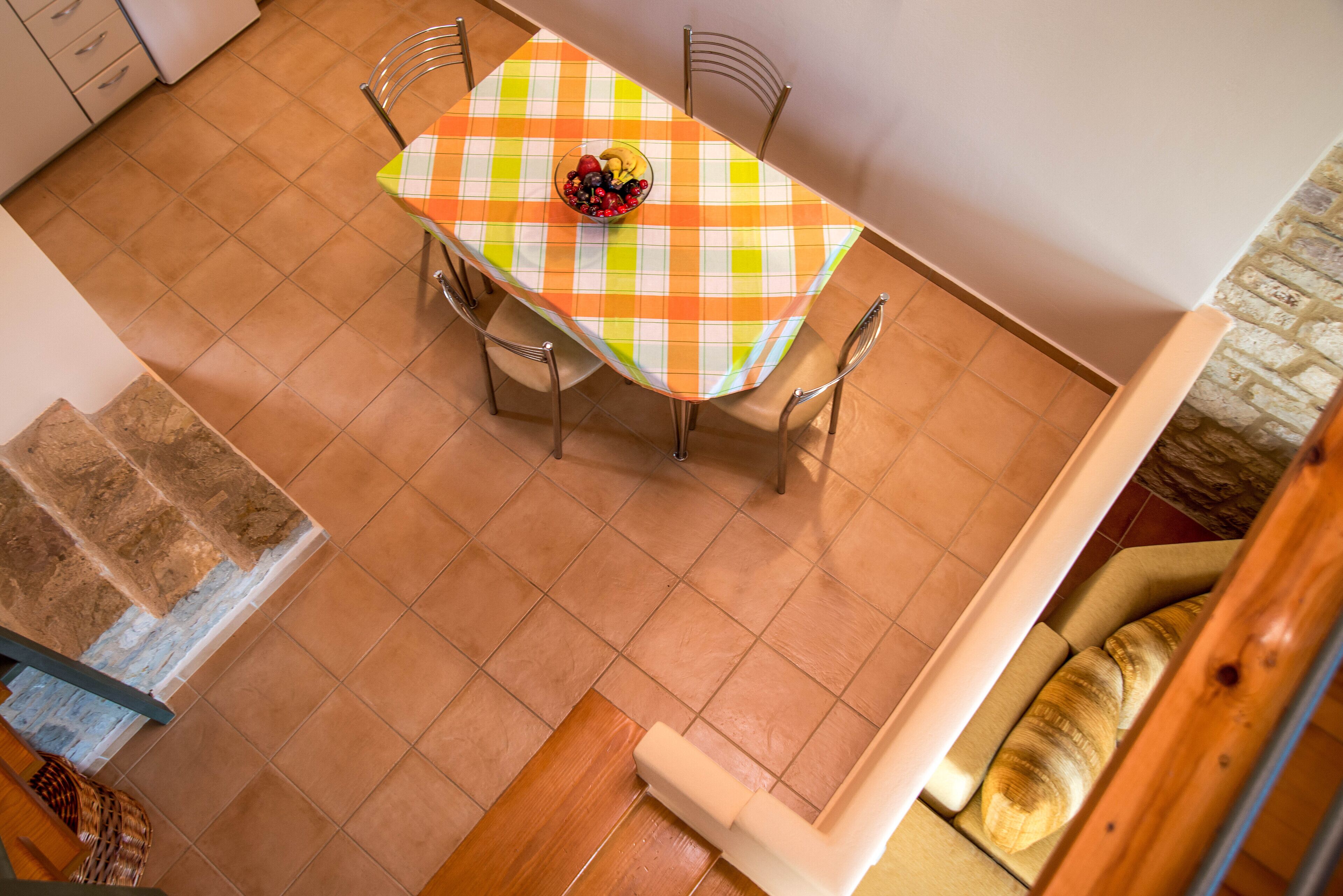 Un comedor con mantel a cuadros, un cuenco de fruta y una hogaza de pan sobre una mesa de madera.