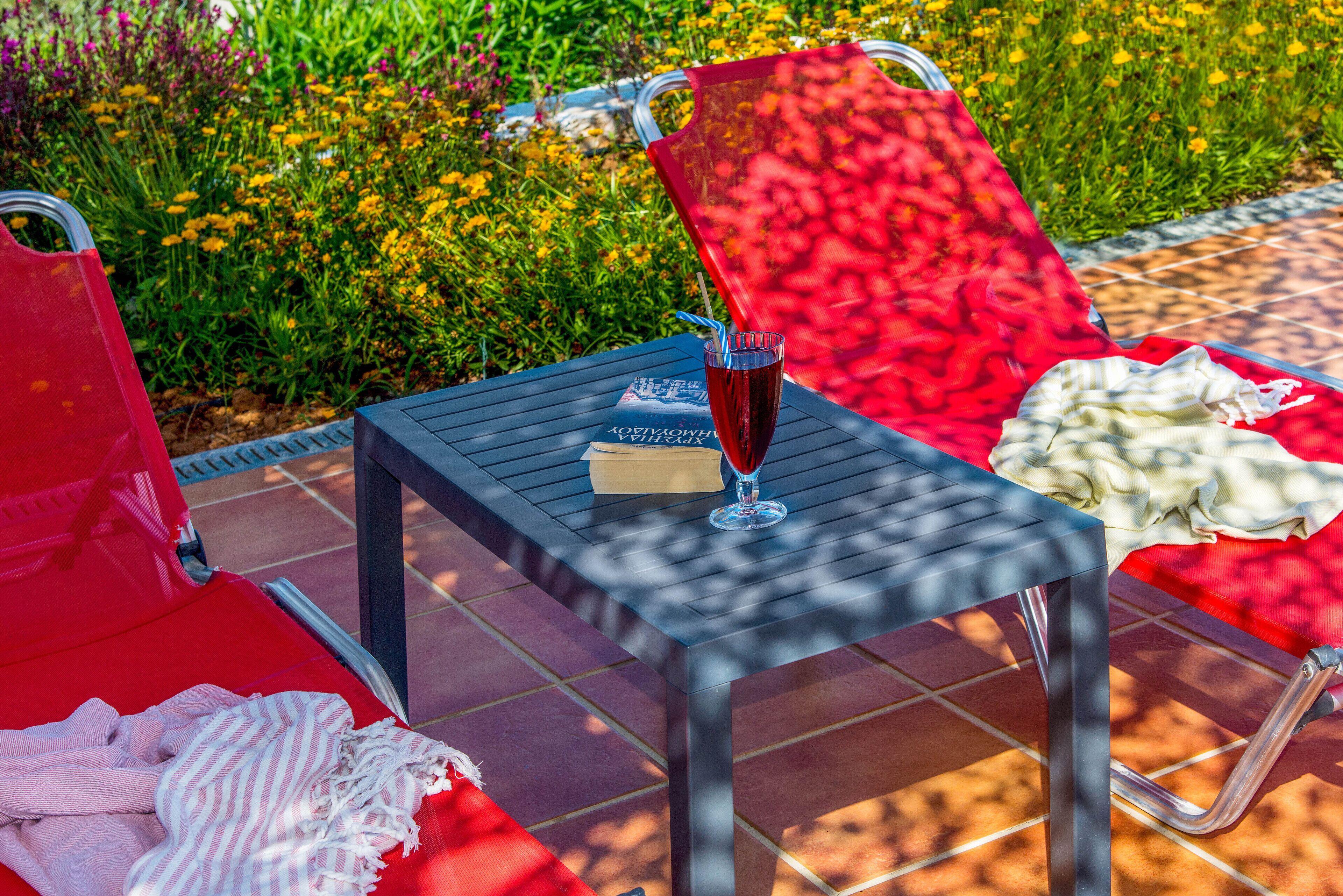 A patio area with a table, chairs, and a glass of red beverage.