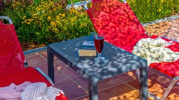 A patio area with a table, chairs, and a glass of red beverage.