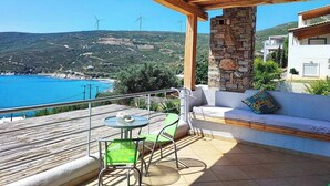 A terrace with a stone pillar, a wooden pergola, a sofa, and a table with chairs. - Seagulls - Within walking distance from sea! (Agioi Apostoloi)