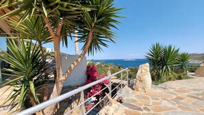 A stone pathway leading to a balcony overlooking the sea, with palm trees and pink flowers. - Seagulls - Within walking distance from sea! (Agioi Apostoloi)
