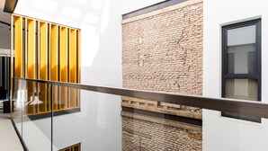 Un interior moderno con barandilla de cristal, pared de ladrillo y ventana.