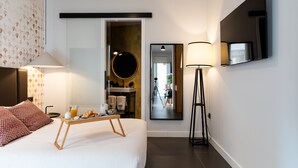 Una habitación de hotel moderna con una cama, mesita de noche, lámpara y bandeja para el desayuno.