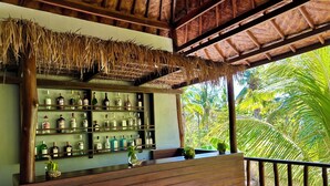 A bar area with a wooden counter and shelves of liquor bottles. - Jungle Paradise (Penida Island)