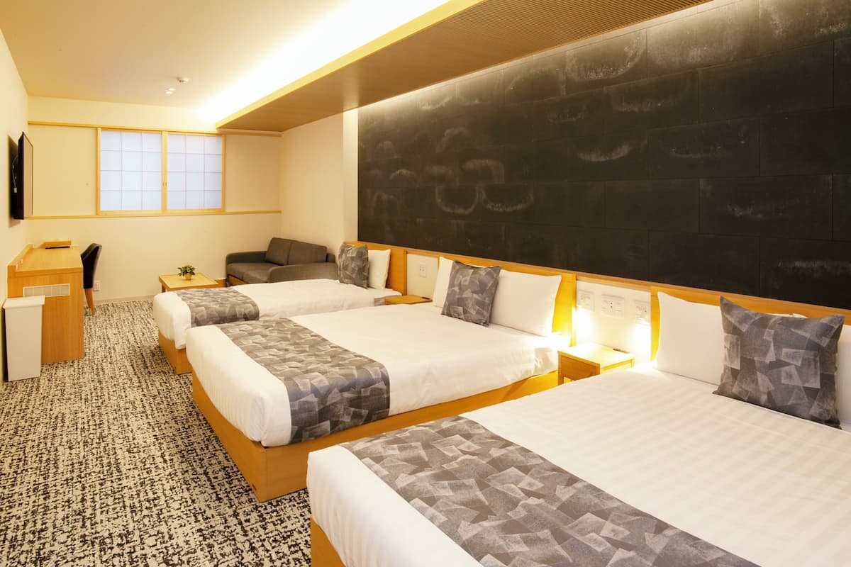 A hotel room with three beds, a desk, a chair, and a large chalkboard wall.