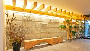 A modern interior with a wooden bench, a stone wall, and wooden beams. - GRAND BASE Osu (Nagoya)