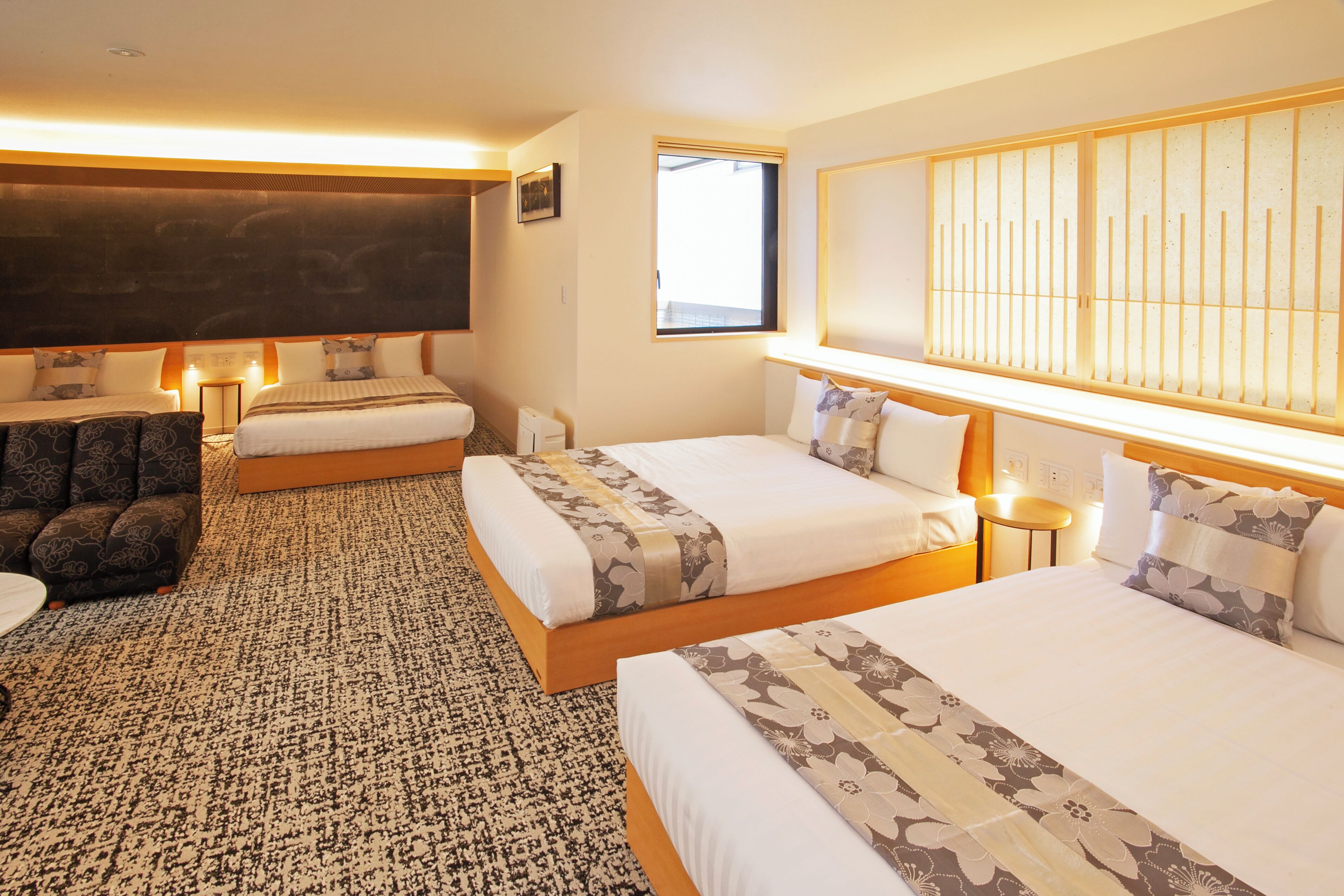 Une chambre d’hôtel avec deux lits, un canapé, une télévision et une grande fenêtre.