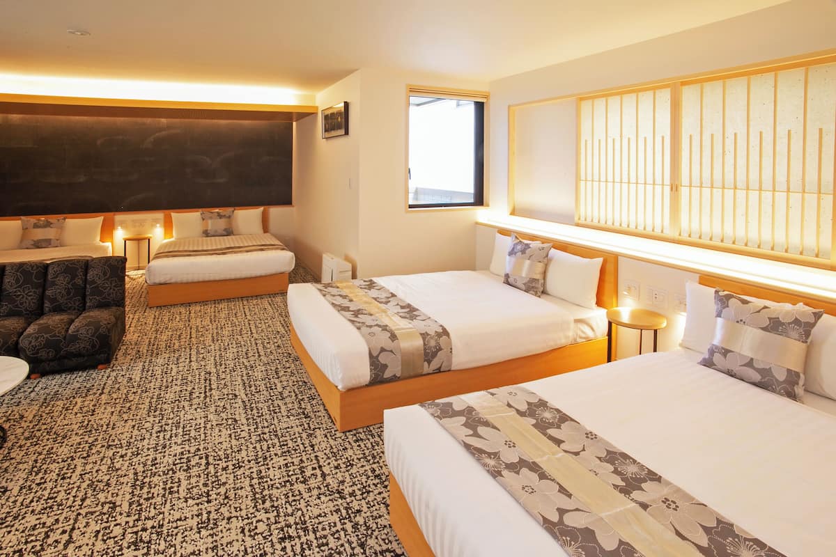 A hotel room with two beds, a sofa, a TV, and a large window.