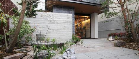 Una casa moderna con un camino de piedra, una valla de madera y una variedad de plantas.